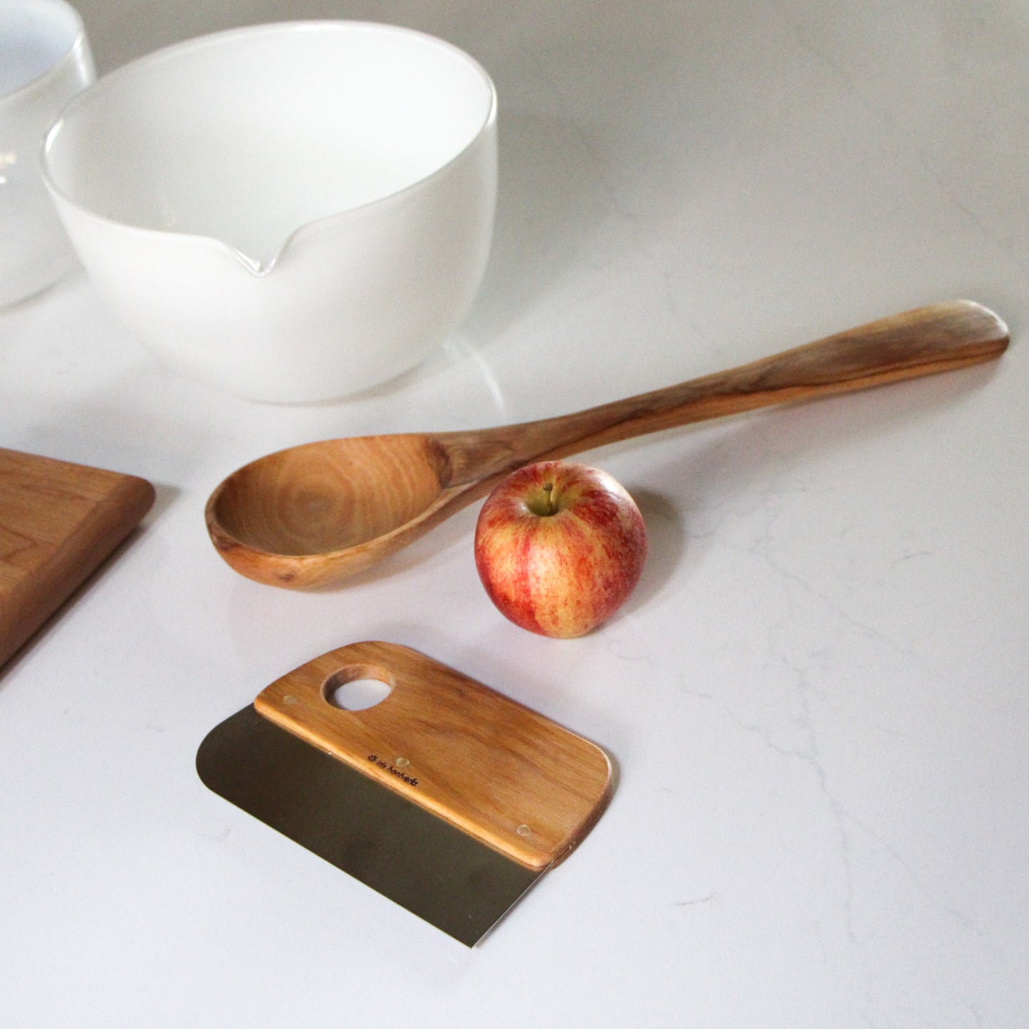 dough scraper with oil-treated birch handle and a strong stainless steel blade shown with glass mixing bowl and large wooden spoon