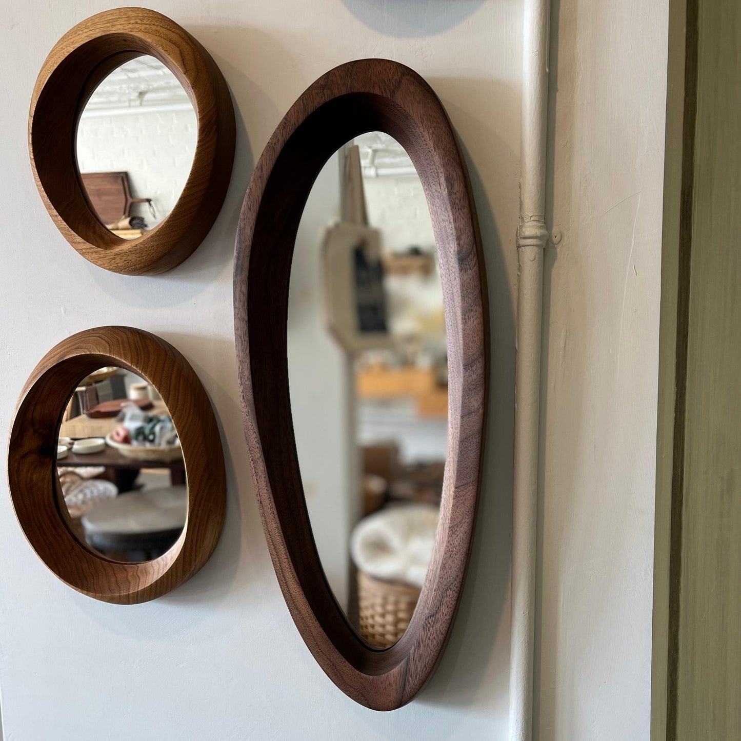 various sizes of hand-carved wooden wall mirrors each with one-of-a-kind organic shape and curves shown in butternut and walnut