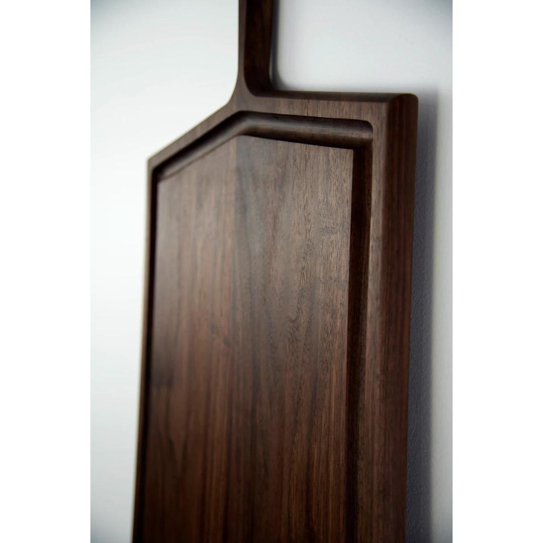 Close up of oversized rectangular carving board in walnut wood with handle and leather strap