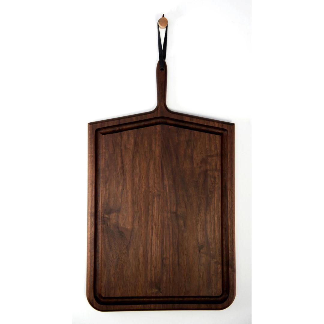 Oversized rectangular carving board in walnut wood with handle and leather strap hanging on wall hook